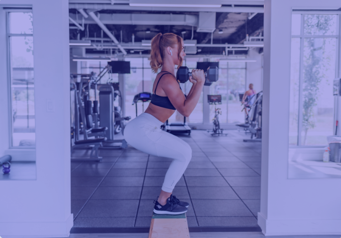 Woman lifting weights with the guidance of a 1 to 1 personal trainer.